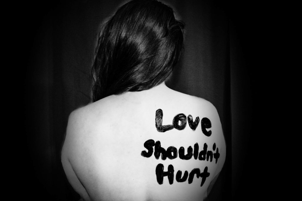 Woman with Love Shouldn't Hurt written on her back